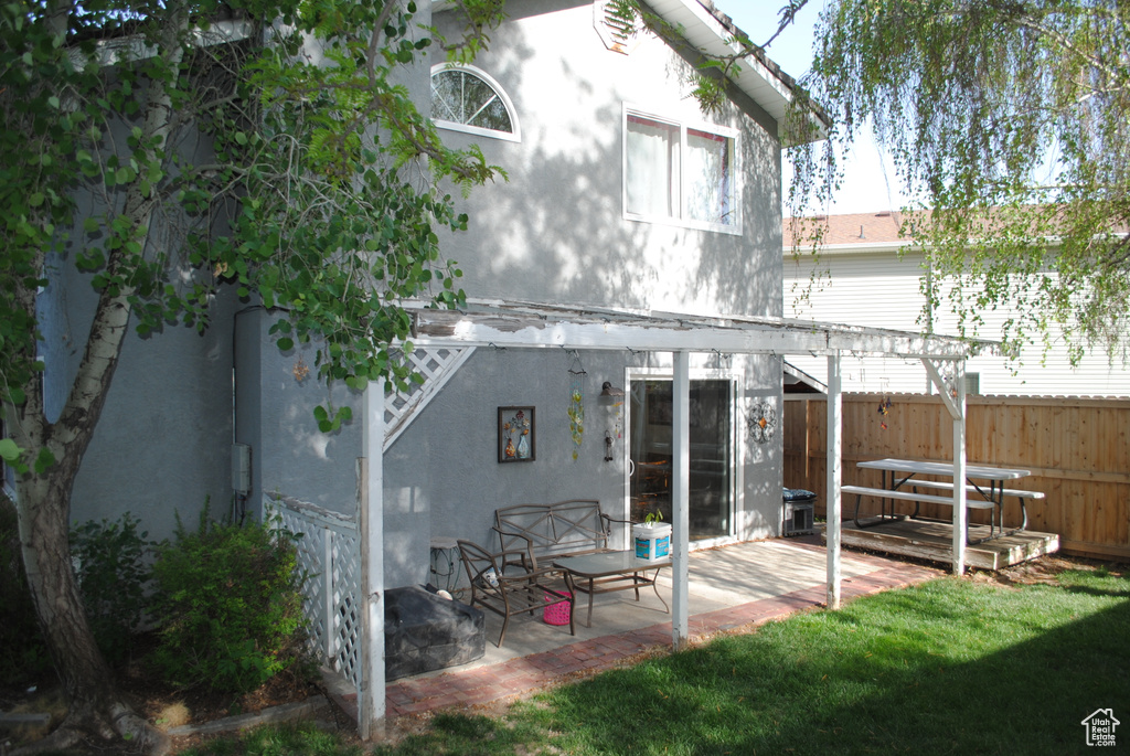 Rear view of property featuring fence, a patio area, and stucco siding