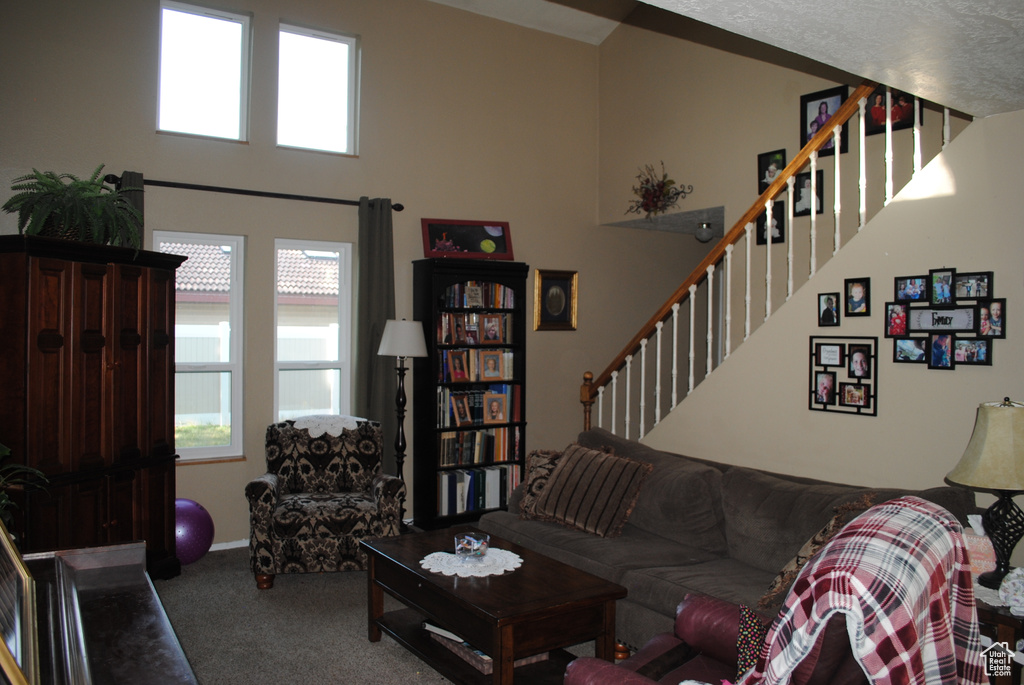 Carpeted living area featuring stairway and a towering ceiling