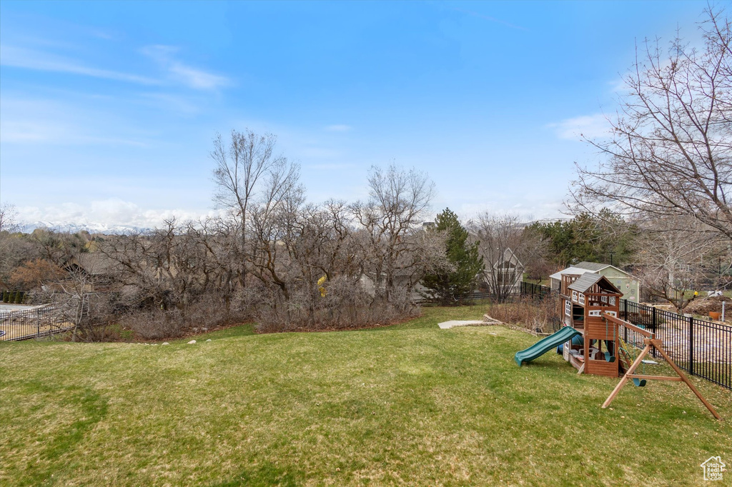 View of yard with a playground and view of scattered trees