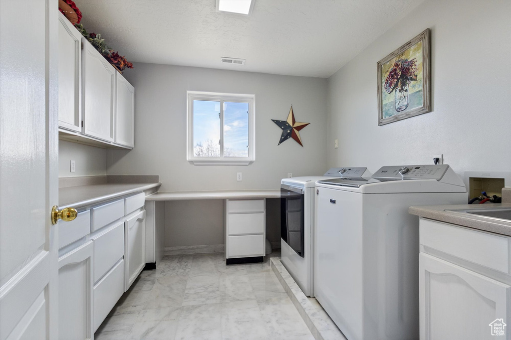 Laundry area featuring cabinet space, washer and dryer, and light marble finish flooring