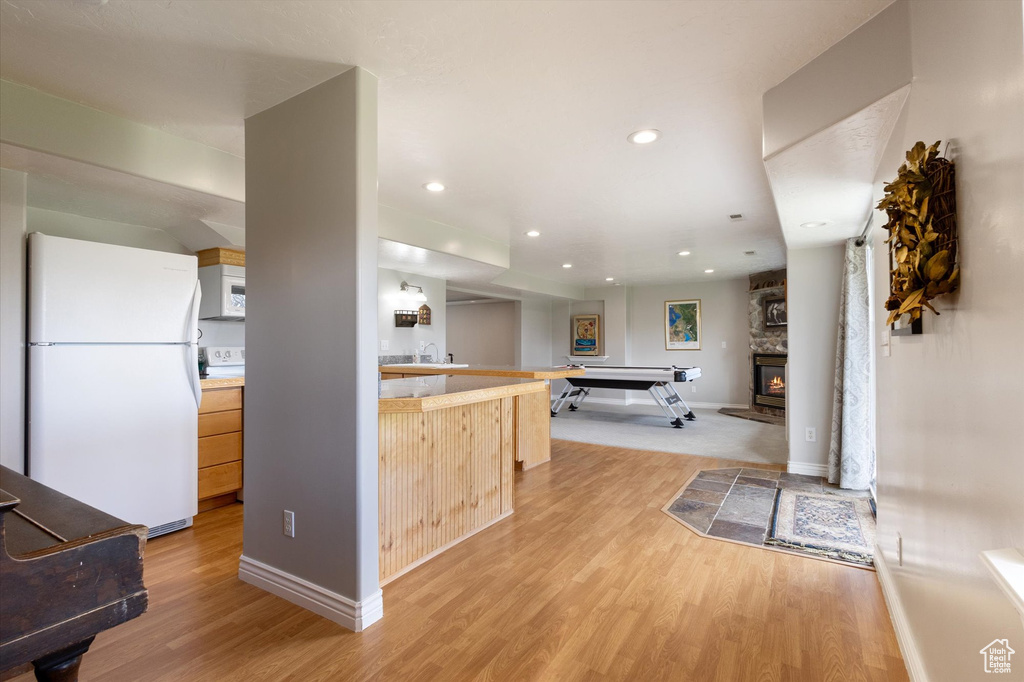 Kitchen with white appliances, light wood-style flooring, light countertops, light brown cabinets, and recessed lighting