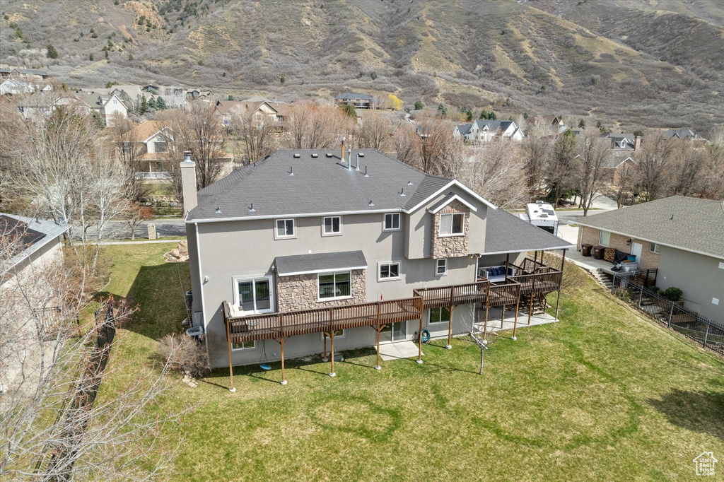 Back of house featuring stucco siding, a deck with mountain view, a chimney, a residential view, and stone siding