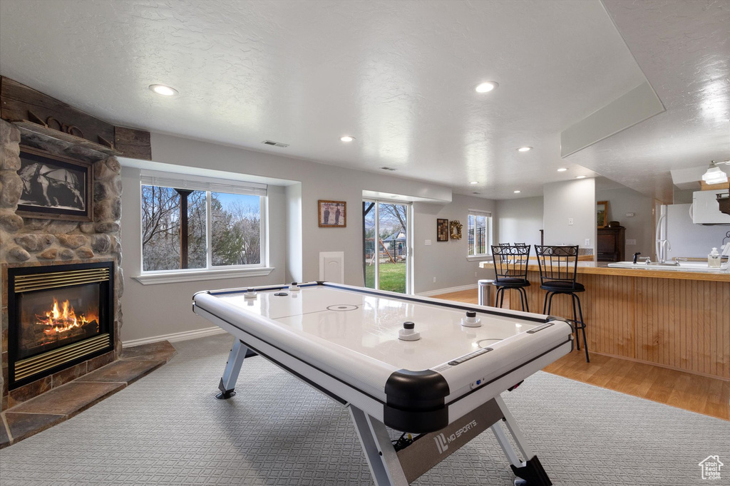 Playroom with a stone fireplace, recessed lighting, baseboards, and wood finished floors
