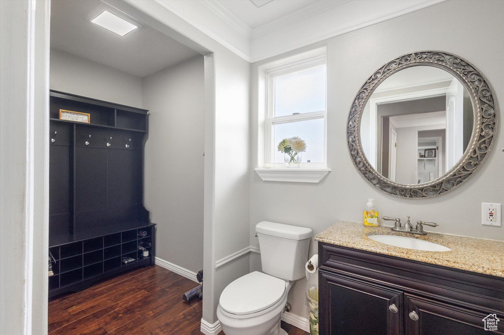 Bathroom featuring wood finished floors, toilet, crown molding, baseboards, and vanity