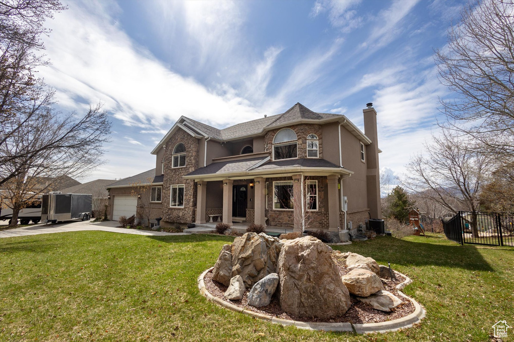 View of front of house featuring a chimney, a garage, concrete driveway, covered porch, and cooling unit
