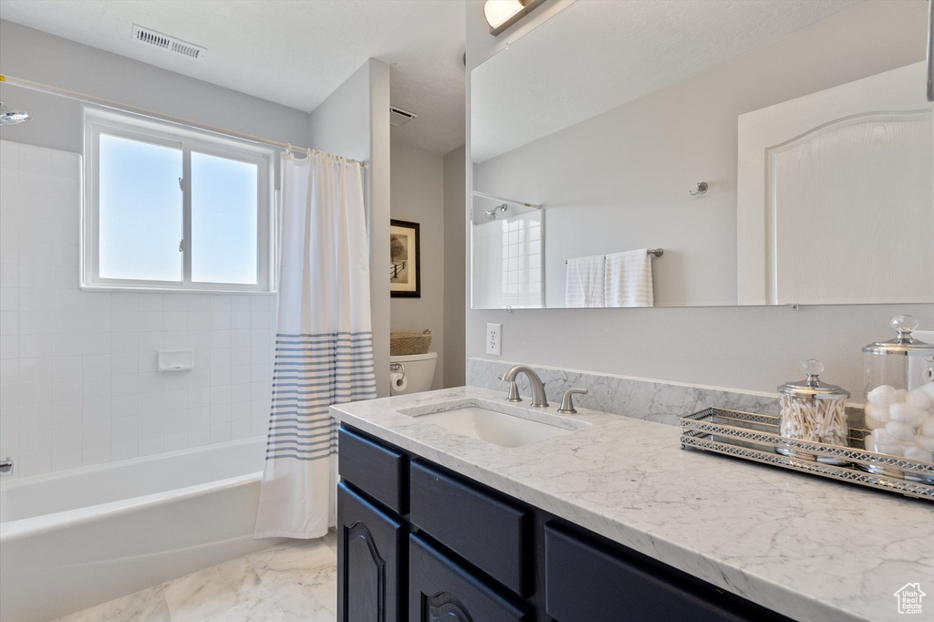 Full bath featuring shower / tub combo with curtain, vanity, marble finish floors, and toilet