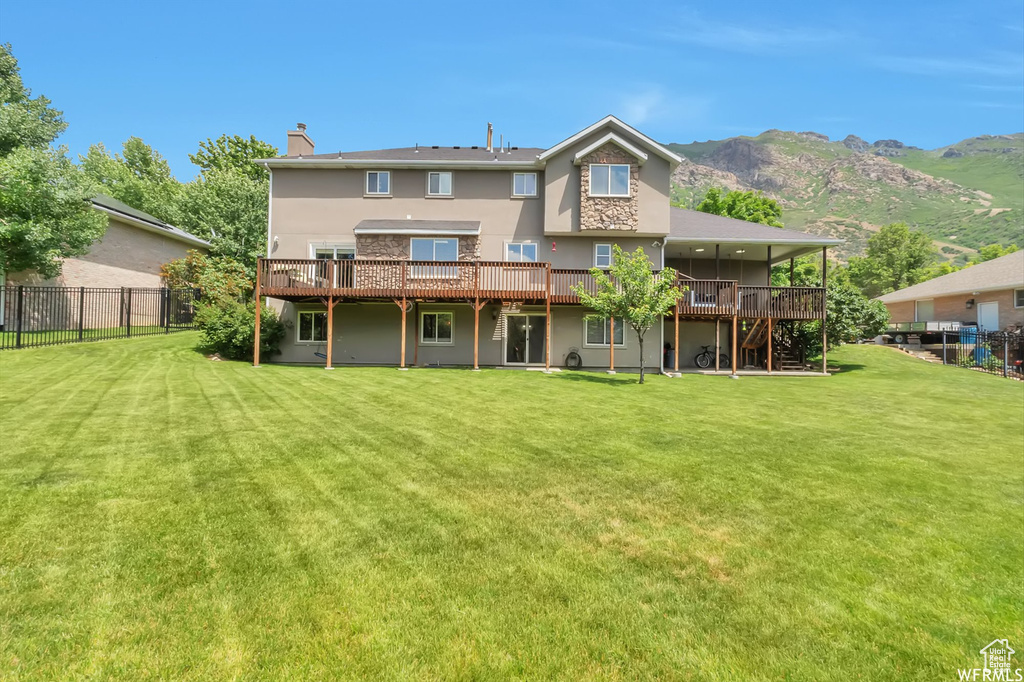 Back of property with a deck with mountain view, a chimney, and stucco siding