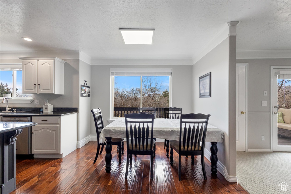 Dining room with dark wood-style flooring, crown molding, and baseboards
