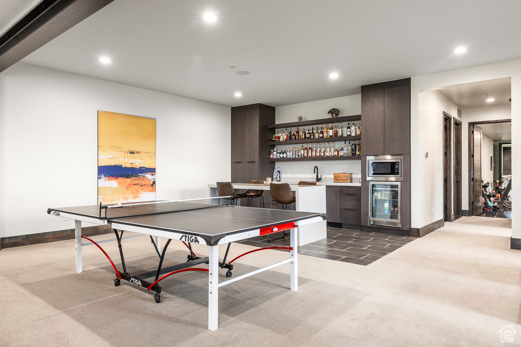 Recreation room featuring beverage cooler, carpet flooring, bar with sink, recessed lighting, and baseboards