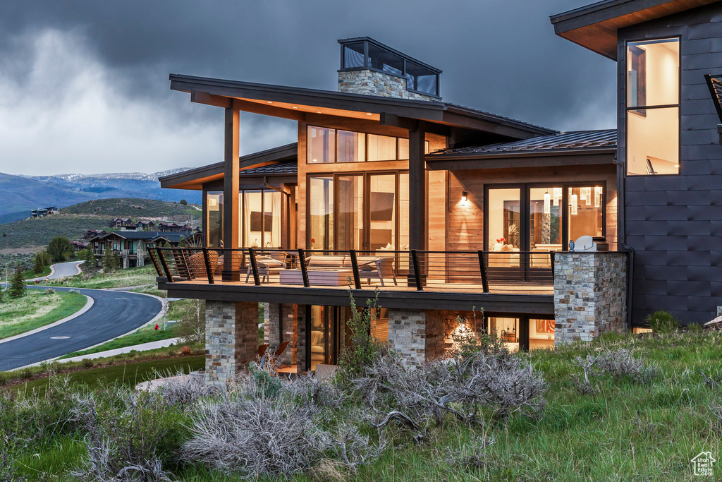 Back of house featuring a mountain view, a balcony, metal roof, and a chimney
