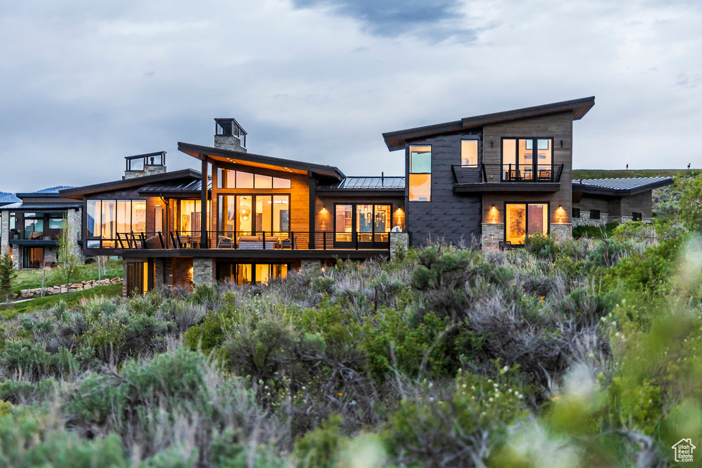 Rear view of property featuring a standing seam roof, stone siding, and metal roof