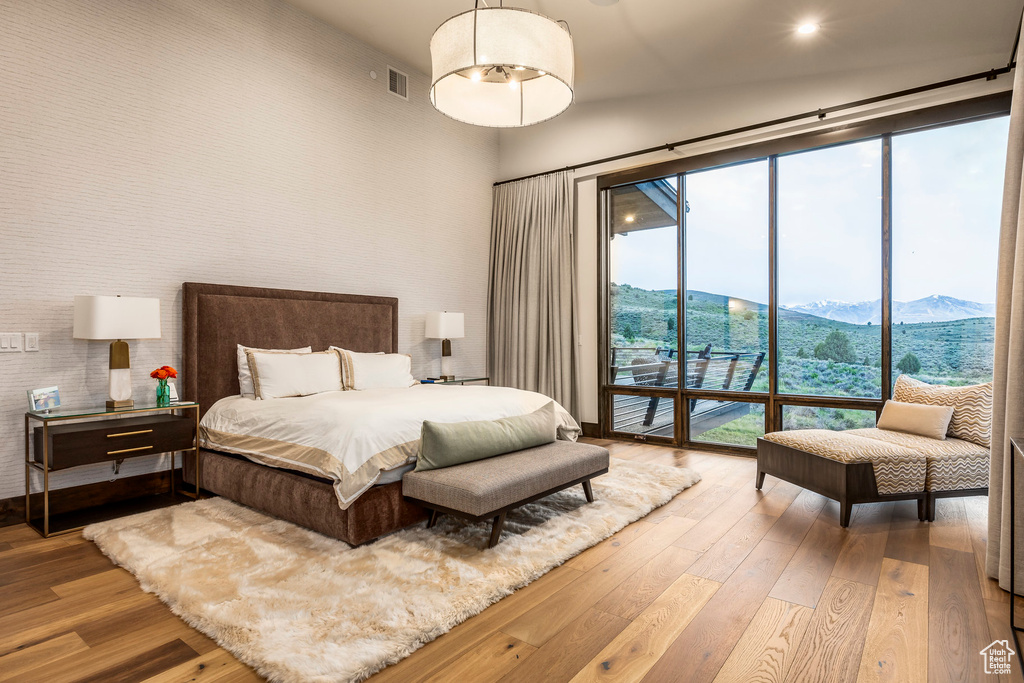 Bedroom with access to outside, hardwood / wood-style floors, a mountain view, and a towering ceiling
