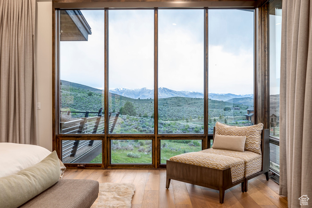 Bedroom with light wood-style flooring, a mountain view, and expansive windows
