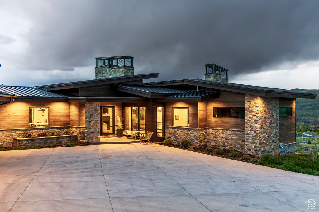 View of front of property featuring a standing seam roof, stone siding, and metal roof