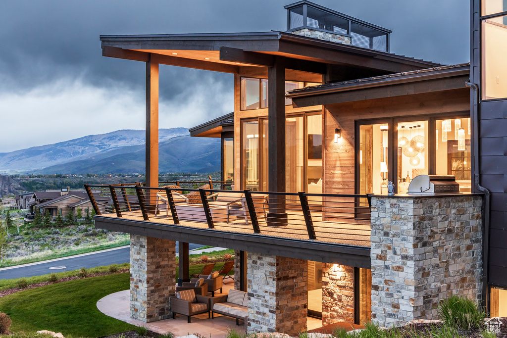 Rear view of property with exterior kitchen, a balcony, and a mountain view