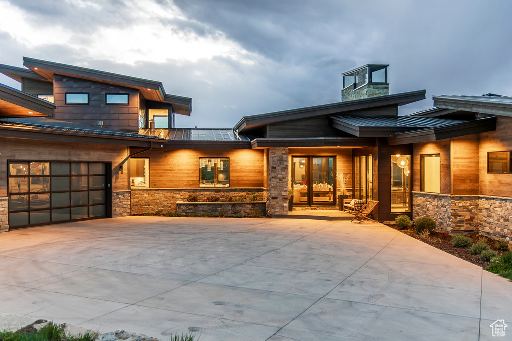 View of front of house with a standing seam roof, metal roof, concrete driveway, and stone siding