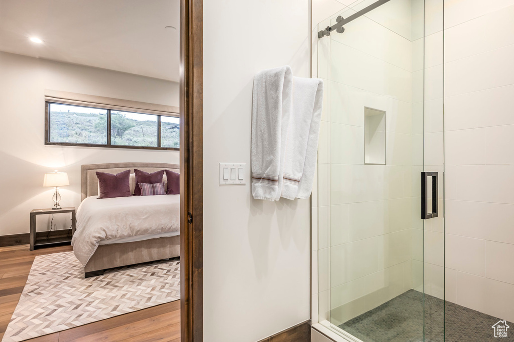 Ensuite bathroom featuring a shower stall, wood finished floors, baseboards, and recessed lighting