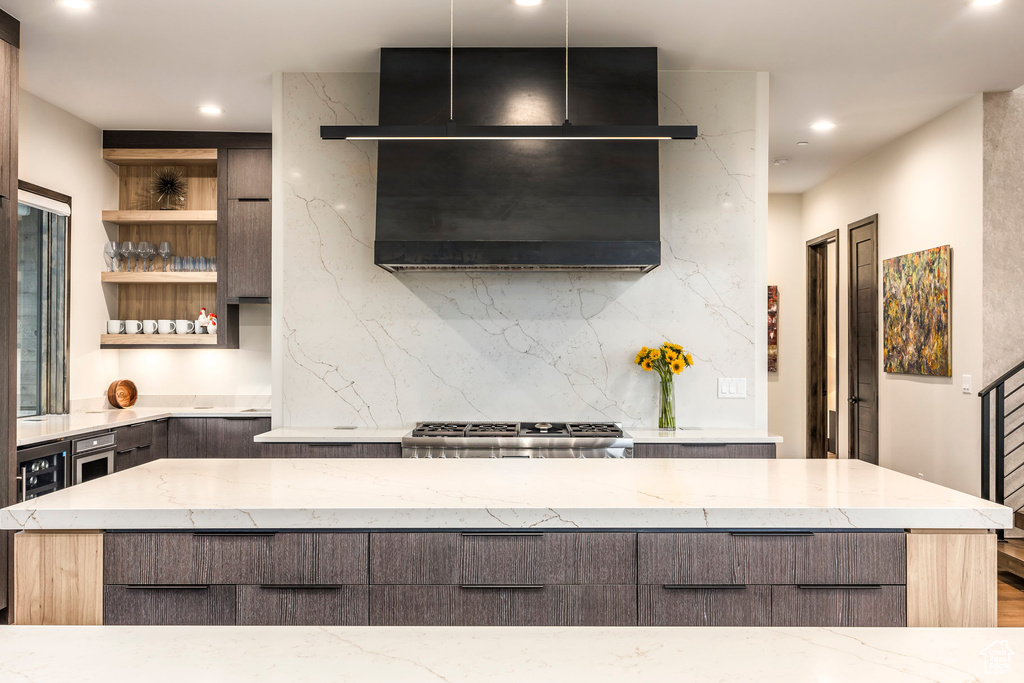 Kitchen with decorative backsplash, light stone countertops, recessed lighting, open shelves, and stove