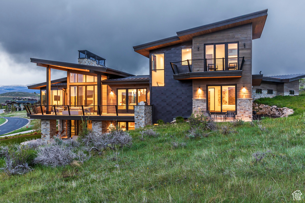 Back of property with a balcony and stone siding