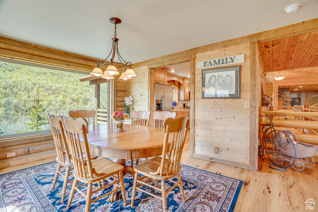 Dining space with wood walls, wood finished floors, and a chandelier