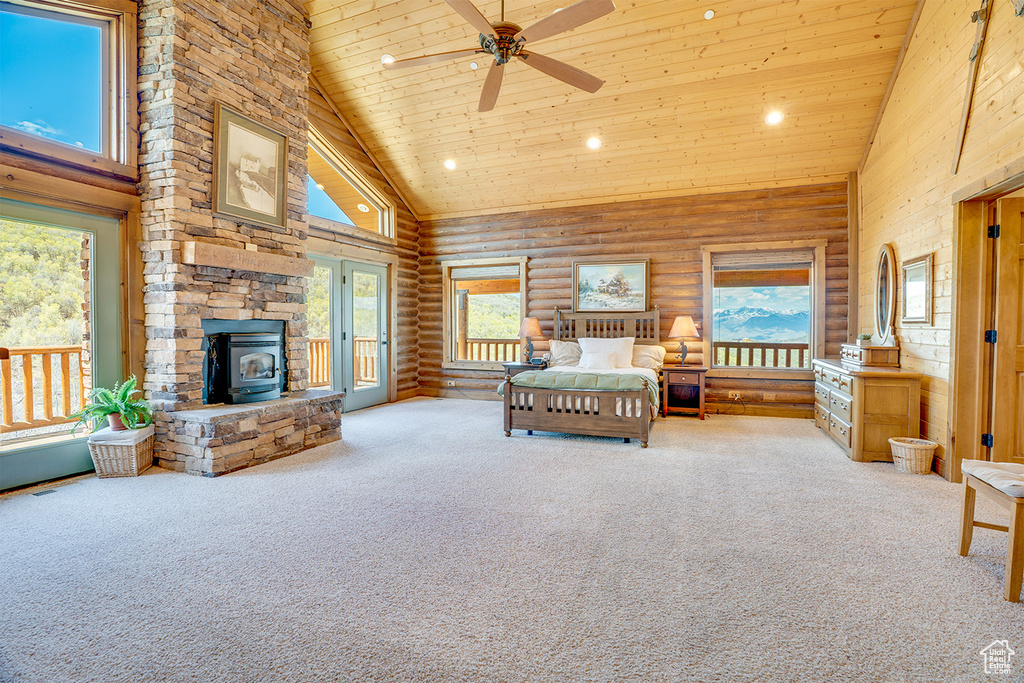Bedroom with high vaulted ceiling, carpet floors, a wood stove, multiple windows, and recessed lighting