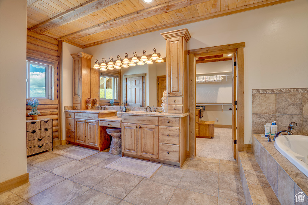 Bathroom with wooden ceiling, a bath, vanity, beam ceiling, and baseboards
