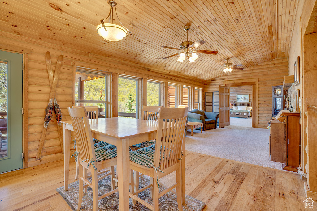 Dining space featuring ceiling fan, light wood finished floors, lofted ceiling, wooden ceiling, and log walls