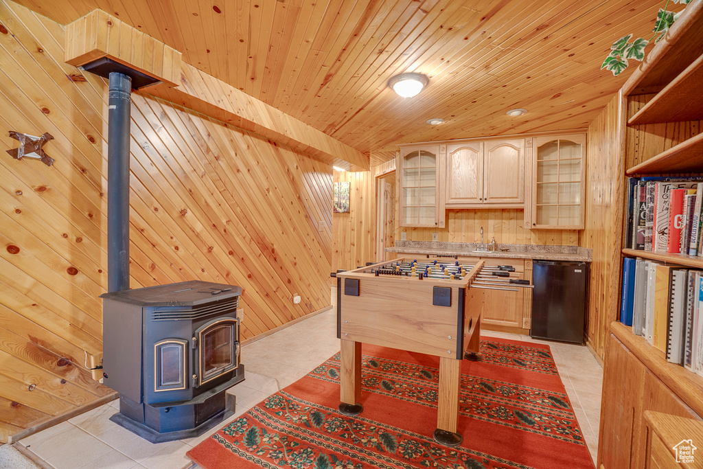 Playroom with wood walls, a wood stove, wood ceiling, a sink, and light tile patterned flooring