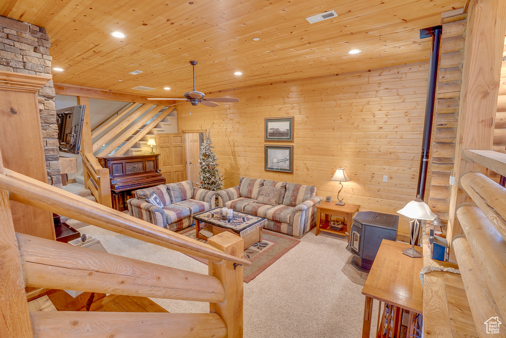 Carpeted living room with a wood stove, recessed lighting, ceiling fan, wood ceiling, and stairway