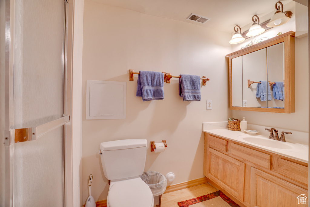 Bathroom with vanity, toilet, and wood finished floors