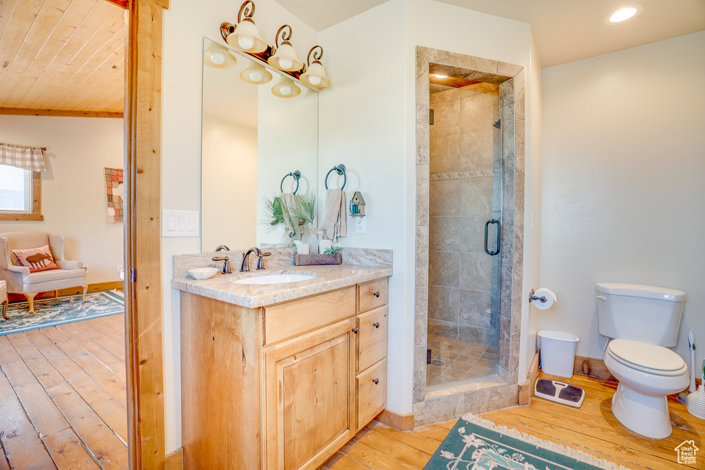 Full bath with hardwood / wood-style flooring, a shower stall, toilet, vanity, and recessed lighting