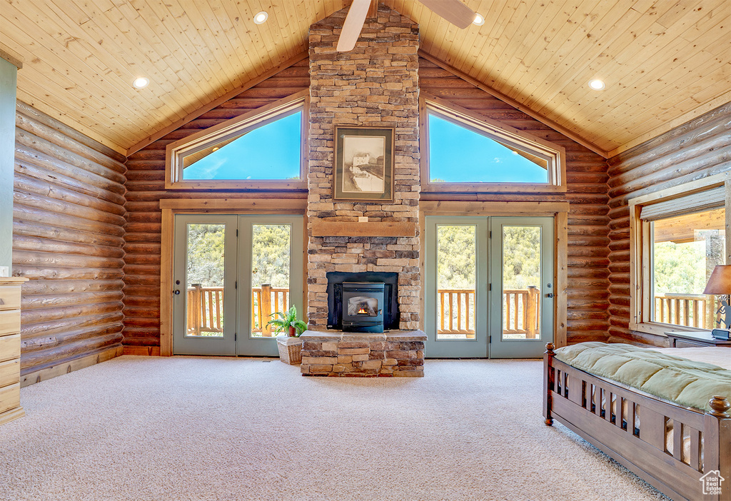 Carpeted bedroom with high vaulted ceiling, wood ceiling, multiple windows, rustic walls, and access to outside