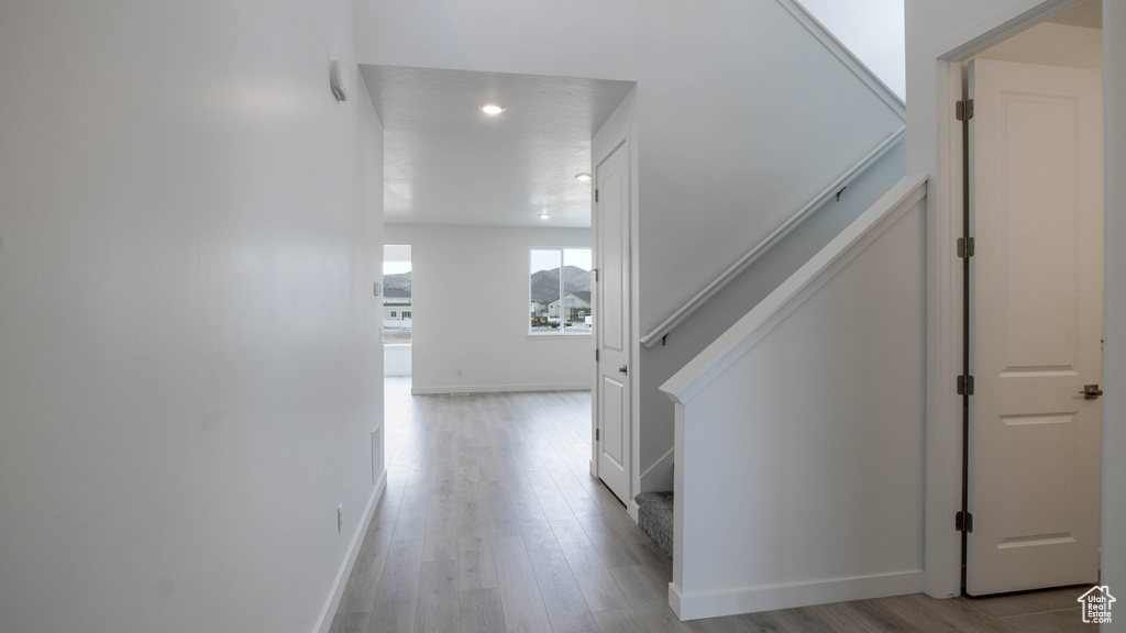 Hallway with stairway, light wood finished floors, baseboards, and recessed lighting