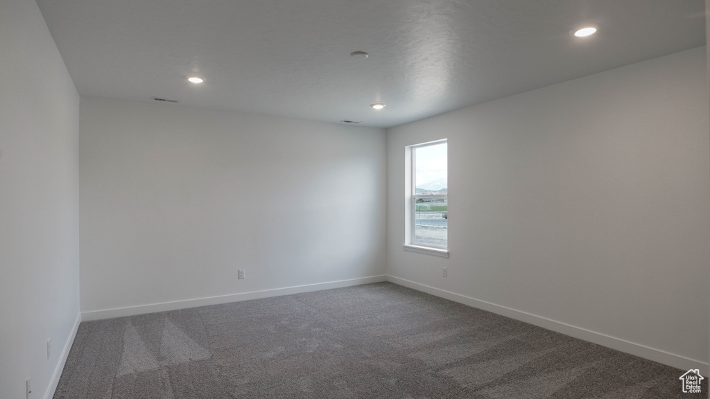 Spare room with dark carpet, baseboards, and recessed lighting