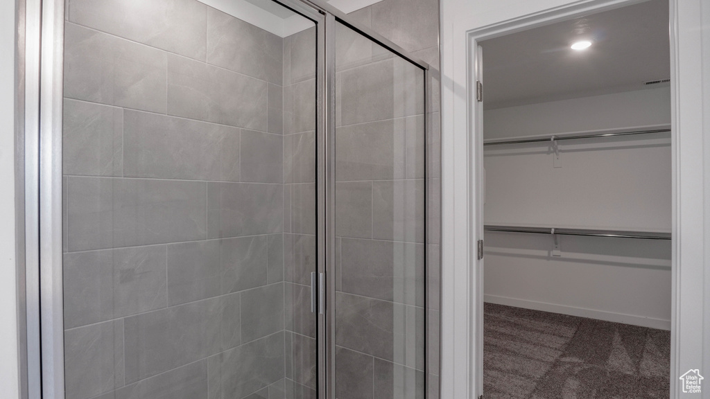 Bathroom featuring a walk in closet, a stall shower, and baseboards