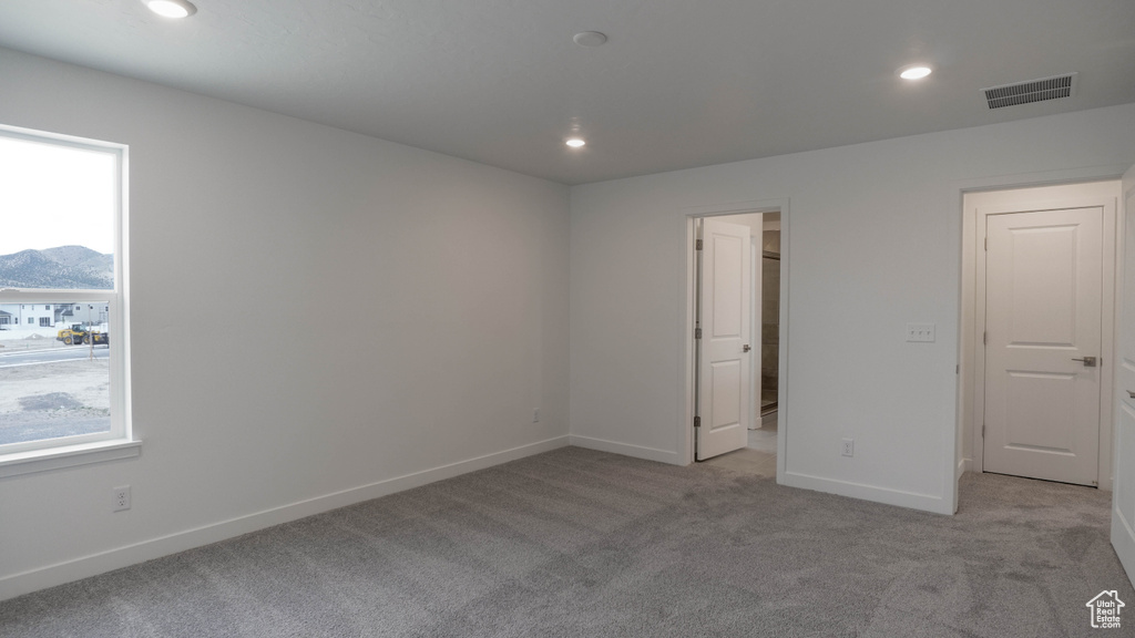 Unfurnished bedroom with light colored carpet, recessed lighting, baseboards, a mountain view, and a walk in closet