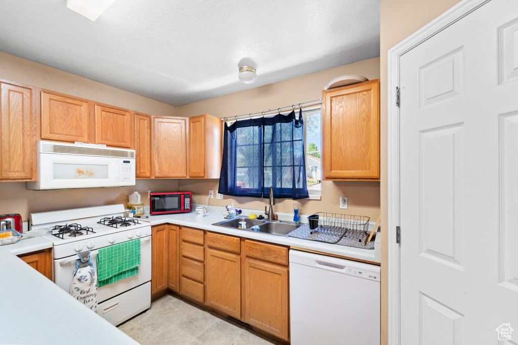Kitchen featuring white appliances, a sink, and light countertops