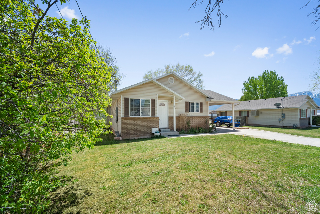 View of front facade with concrete driveway, brick siding, a carport, and a front yard