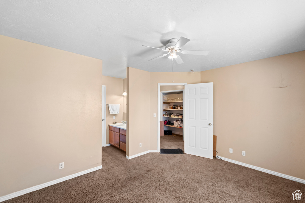 Unfurnished bedroom featuring carpet flooring, a walk in closet, a closet, baseboards, and connected bathroom