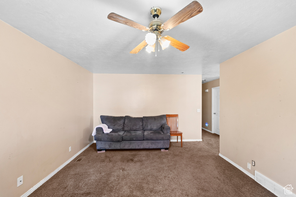 Living area featuring carpet, ceiling fan, and baseboards
