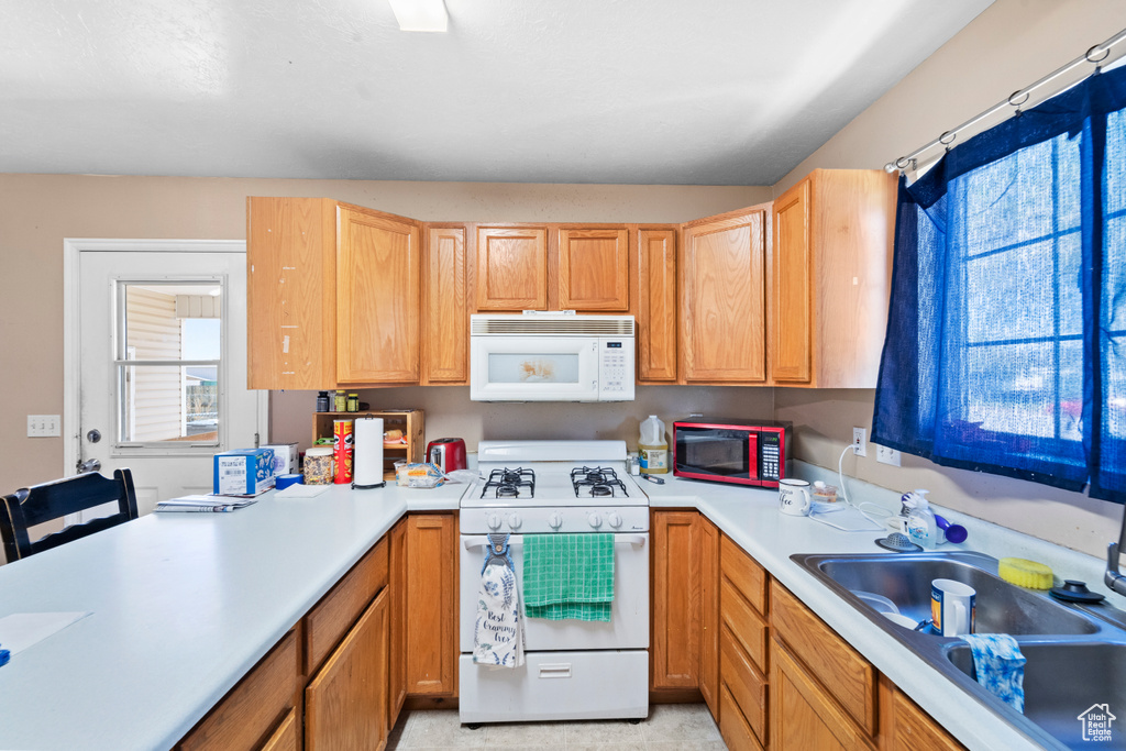 Kitchen with white appliances, healthy amount of natural light, a sink, and light countertops