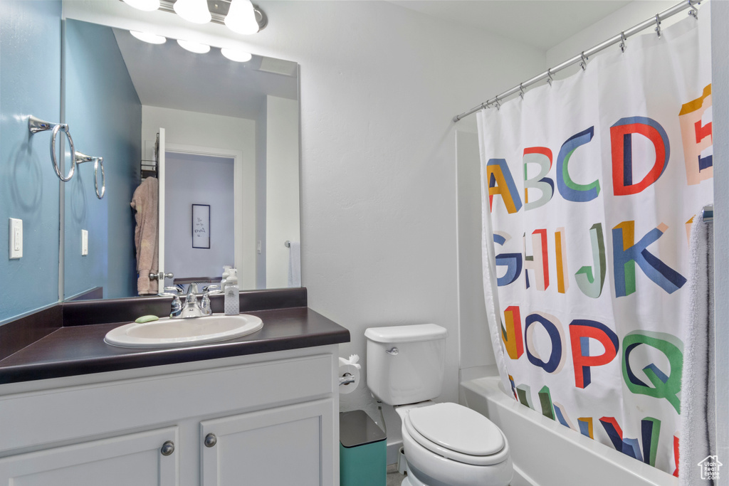 Full bathroom featuring vanity, shower / tub combo with curtain, and toilet