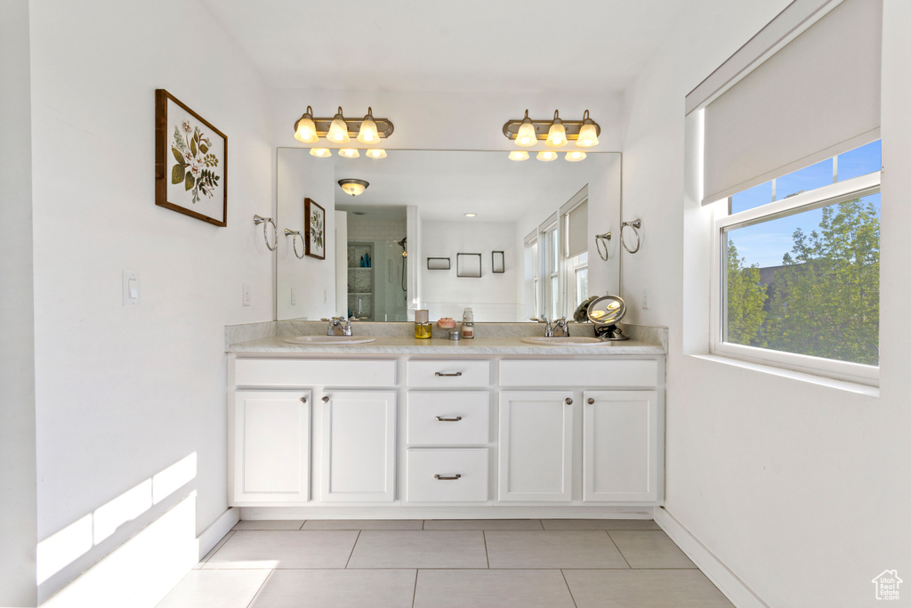 Bathroom with a sink, tile patterned flooring, a stall shower, and double vanity