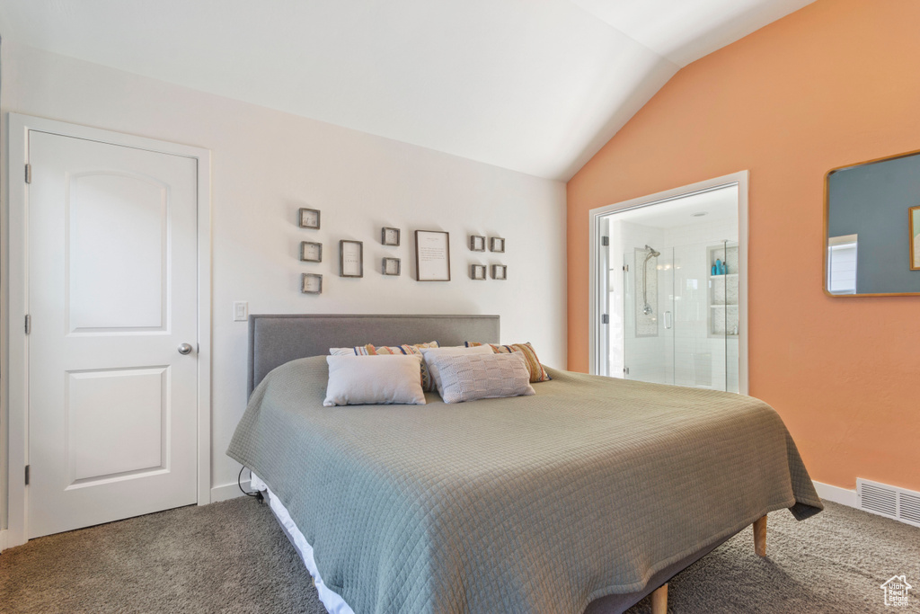 Carpeted bedroom featuring visible vents, baseboards, ensuite bathroom, and vaulted ceiling