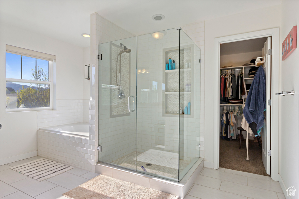 Full bathroom with a walk in closet, tile patterned flooring, baseboards, a shower stall, and a bath