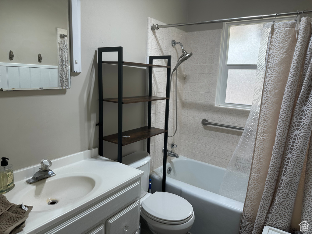 Full bathroom featuring shower / bath combination with curtain, toilet, and vanity