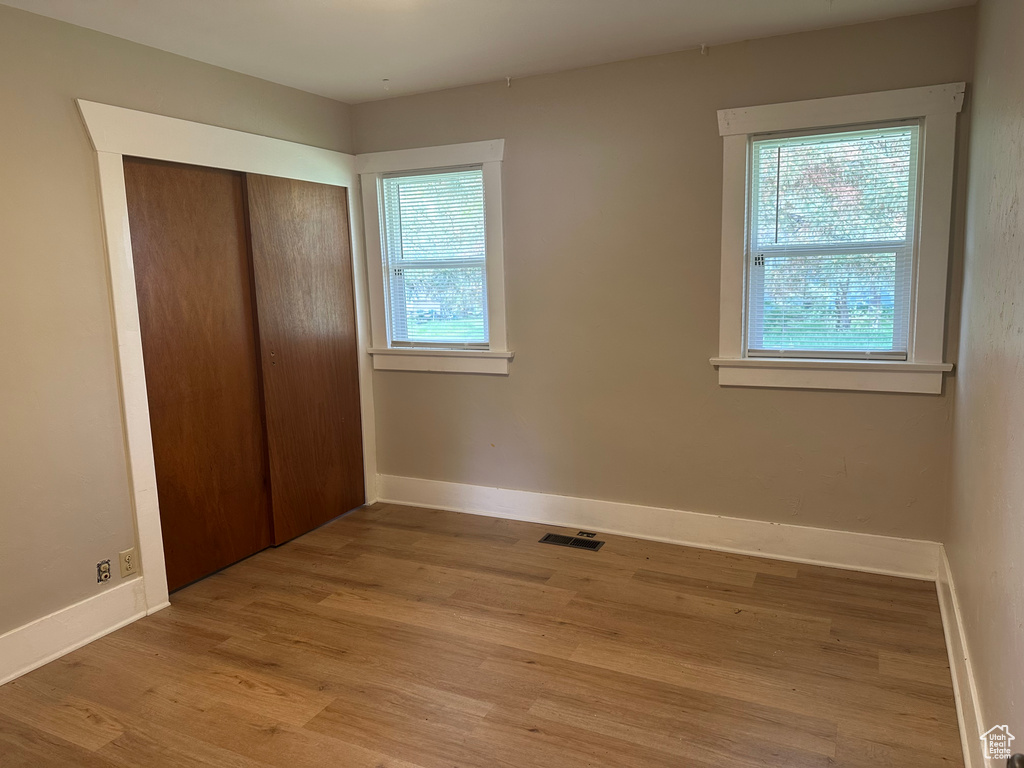 Unfurnished bedroom featuring light wood finished floors, baseboards, and a closet