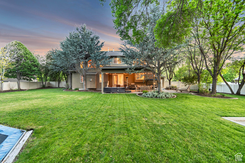 Back of property at dusk with a patio and an outdoor living space
