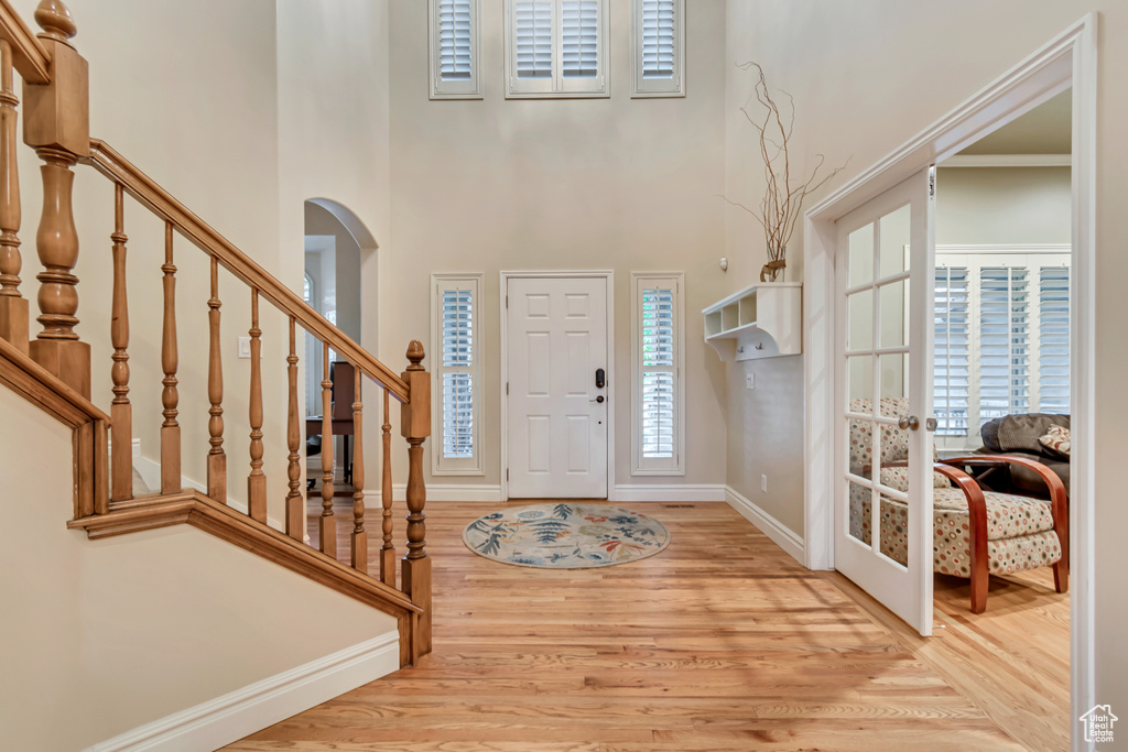 Foyer featuring baseboards, wood finished floors, stairway, and a high ceiling