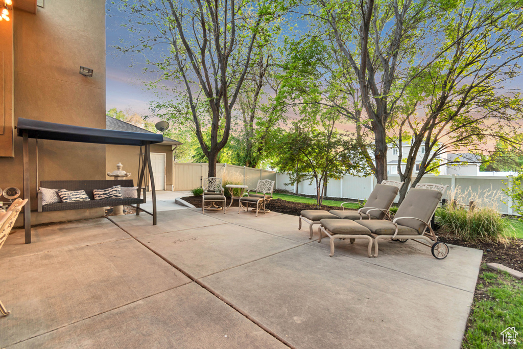 Patio terrace at dusk with a fenced backyard and outdoor lounge area